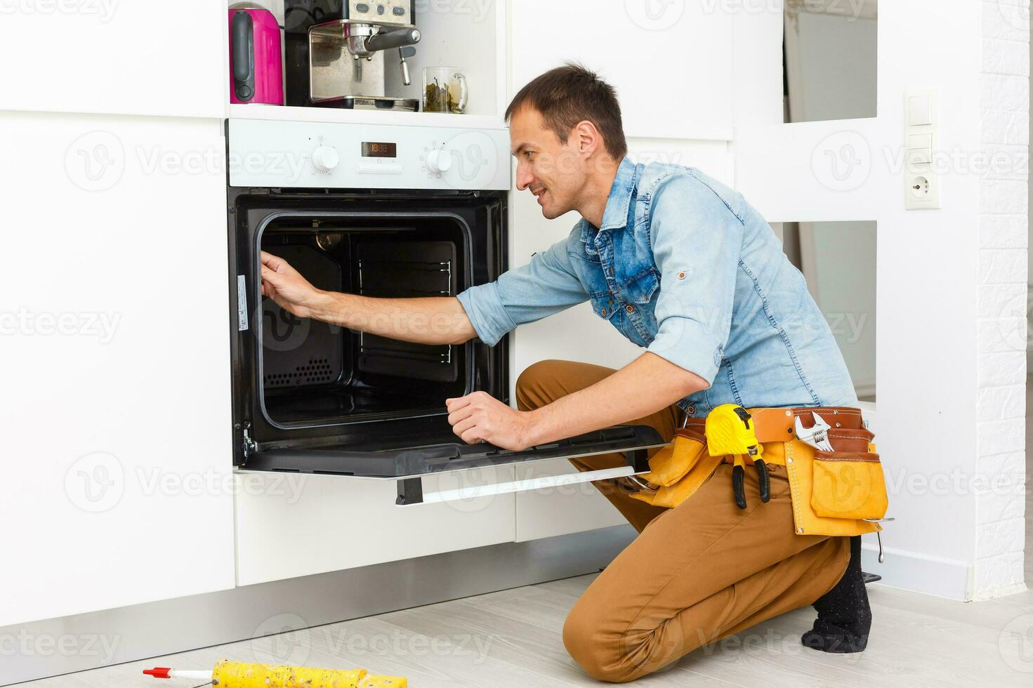 young repairman installing induction cooker in kitchen photo